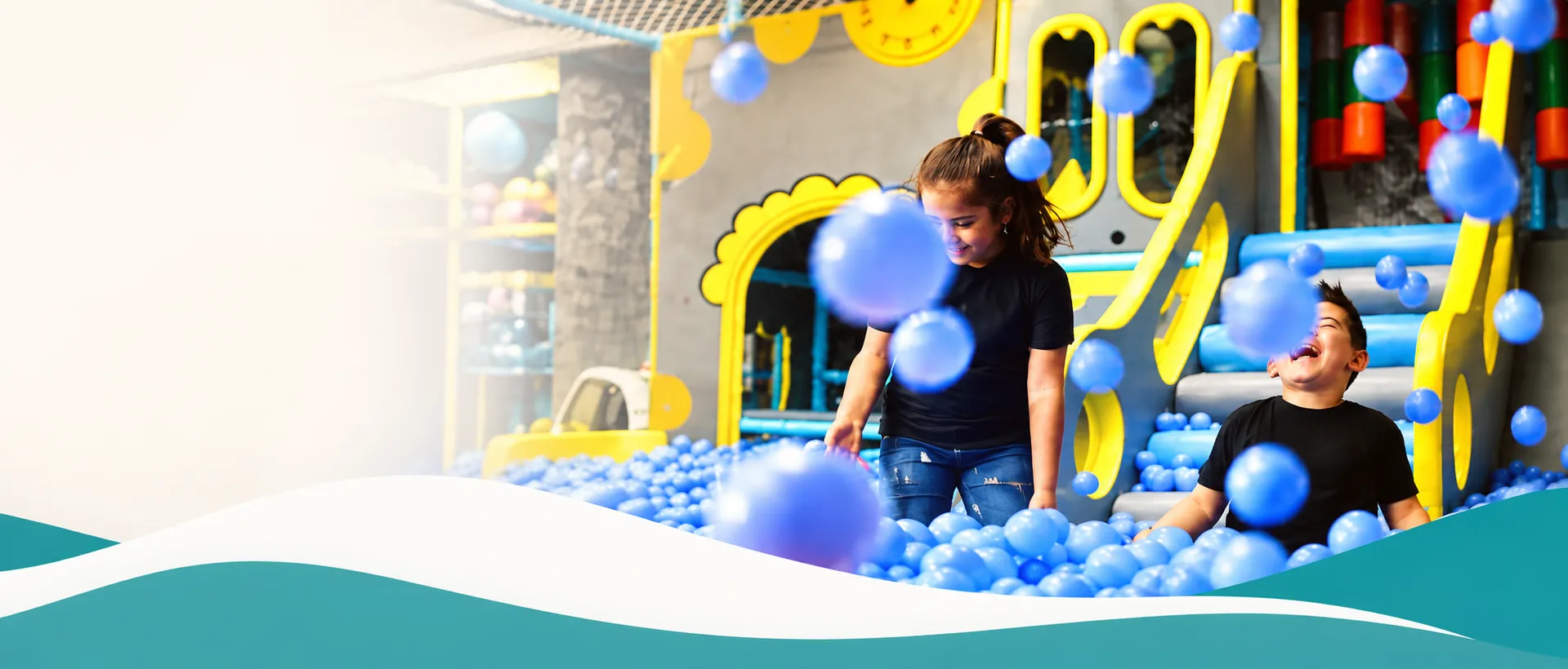 Fetiță și băiat râzând în piscina cu bile albastre din zona de joacă KLANkids, Galeriile Titan București
